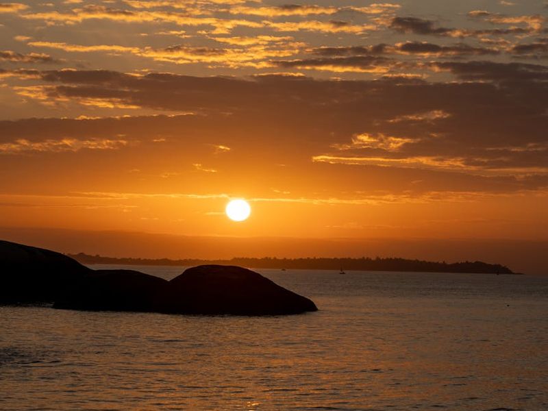 Person doing yoga during golden hour sunset near sea